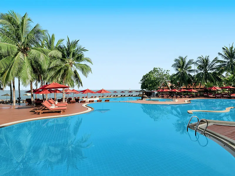 Velik modri bazen s pogledom na morje in rdečimi senčniki v Khaolak Laguna Resortu